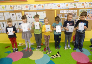 Siedmioro dzieci stoi z kartkami z zapisanymi literami, tworzące hasło relacje.